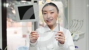 Focus on hands with instruments of happy young female asian dentist with tools