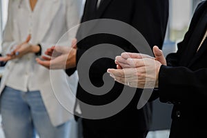 Focus at hands of men wearing black suit and woman white shirt and blue jean applause for congratulation feel happiness at office