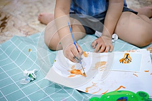 Focus on hands on paper. Children use paintbrushes to paint watercolors on paper to create their imagination and enhance