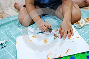 Focus on hands on paper. Children use paintbrushes to paint watercolors on paper to create their imagination and enhance