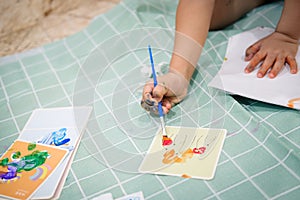 Focus on hands on paper. Children use paintbrushes to paint watercolors on paper to create their imagination and enhance