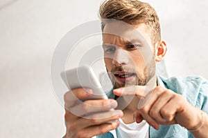 Focus of handsome man pointing with finger at smartphone