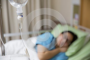 Focus the hanging saline solution with blur patient background.Illness and treatment.