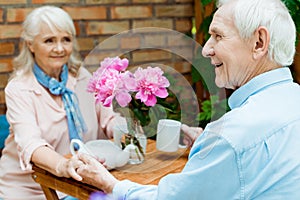 Focus of happy retired man and woman holding hands