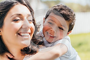 Focus of happy son hugging cheerful mother