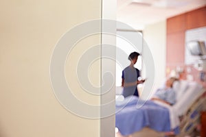 Focus On Hospital Room Sign With Nurse Talking To Patient