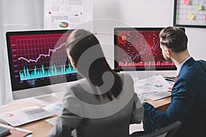 Focus of information security analysts working with computers and papers at table in office