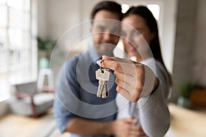 Focus on keys, held by excited young homeowners.