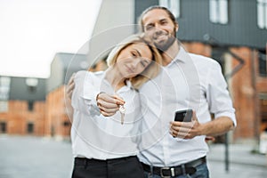 Focus on keys, held by excited young spouses homeowners.