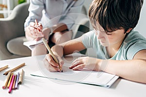 Focus of kid with dyslexia drawing on paper with pencil