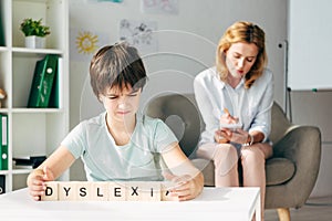 Focus of kid with dyslexia holding cubes with lettering dyslexia