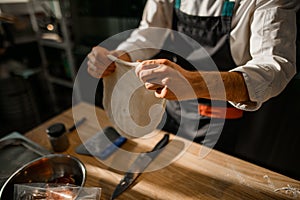 focus on male hands who prepares the dough for the pizza base