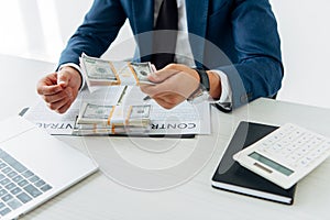 Focus of man holding folder with money near contract with pen