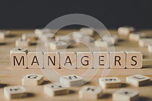 Focus of managers inscription on cubes surrounded by blocks with letters on wooden surface isolated on black