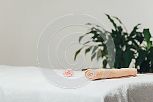 Focus of massage table with rose and beige towel in spa