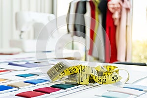 Focus on measuring tape and stack of colorful fabrics on dressmaker`s desk, Tailoring accessories, Fashioner market concept photo