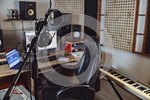 Microphone and headphones in blurred sound engineer office for broadcasting and music rehearsal space. Recording studio