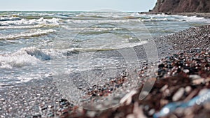 Focus movement from the stormy ocean to the shore with a plastic bottle. The concept of environmental pollution