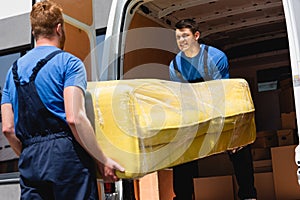 Focus of movers unloading sofa in