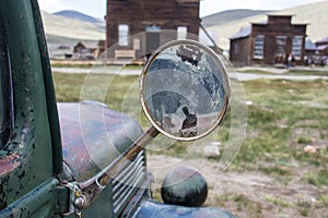 Focus on an old classic rearview mirror on a classic jalopy truck, abandoned in the Bodie Ghost Town in California