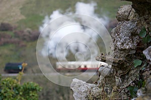 Focus on old stone wall; traditional steam train and carriages in background