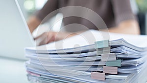 Focus on paperwork, a busy desk with documents and a laptop.