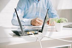 Focus of plugged router near businessman writing in notebook