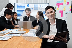 Focus portrait male manager in harmony office with businesspeople in background.