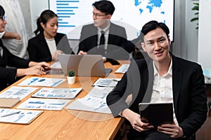 Focus portrait male manager in harmony office with businesspeople in background.