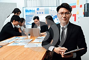 Focus portrait male manager in harmony office with businesspeople in background.