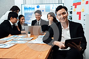 Focus portrait male manager in harmony office with businesspeople in background.