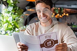 Focus of positive man holding menu in restaurant