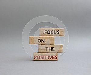 Focus on the Positives symbol. Concept word Focus on the Positives on wooden blocks. Beautiful grey background. Business and Focus