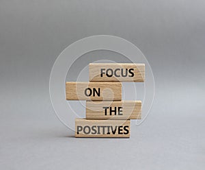 Focus on the Positives symbol. Concept word Focus on the Positives on wooden blocks. Beautiful grey background. Business and Focus