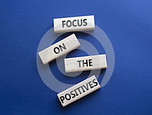 Focus on the Positives symbol. Concept words Focus on the Positives on wooden blocks. Beautiful deep blue background. Business