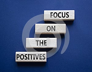 Focus on the Positives symbol. Concept words Focus on the Positives on wooden blocks. Beautiful deep blue background. Business