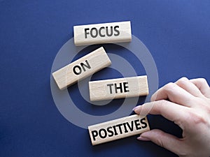 Focus on the Positives symbol. Concept words Focus on the Positives on wooden blocks. Beautiful deep blue background. Businessman