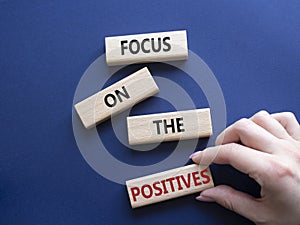 Focus on the Positives symbol. Concept words Focus on the Positives on wooden blocks. Beautiful deep blue background. Businessman