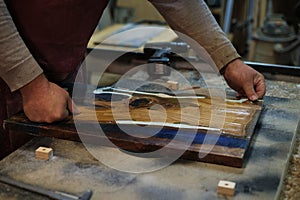 The focus and precision of a carpenter are evident as he sands down a wooden board, immersed in the process of shaping