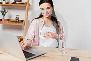 Focus of pregnant woman using laptop