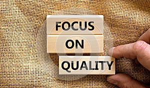 Focus on quality symbol. Concept words Focus on quality on blocks on beautiful canvas table canvas background. Businessman hand.