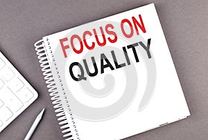 FOCUS ON QUALITY text on the notebook with calculator and pen