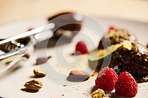 Focus on ripe raspberries on a white plate with chocolate ice cream