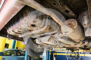 Focus on rusty, damaged, corroded undercarriage of car at workshop