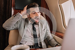 Focus of shocked businessman with open mouth looking in porthole in private jet