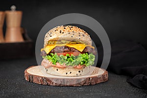 Focus shot of a delicious Angus burger places on a wood placemat in front of a black background.