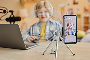 Focus on smartphone screen with cute schoolboy clicking mouse