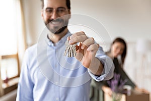 Focus on smiling bearded man in eyeglasses showing keys to camera.