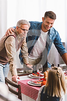 Focus of smiling father and grandparent looking at kid in Thanksgiving day