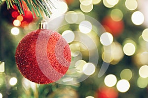 Focus sparkling glitter red ball on blur Christmas tree